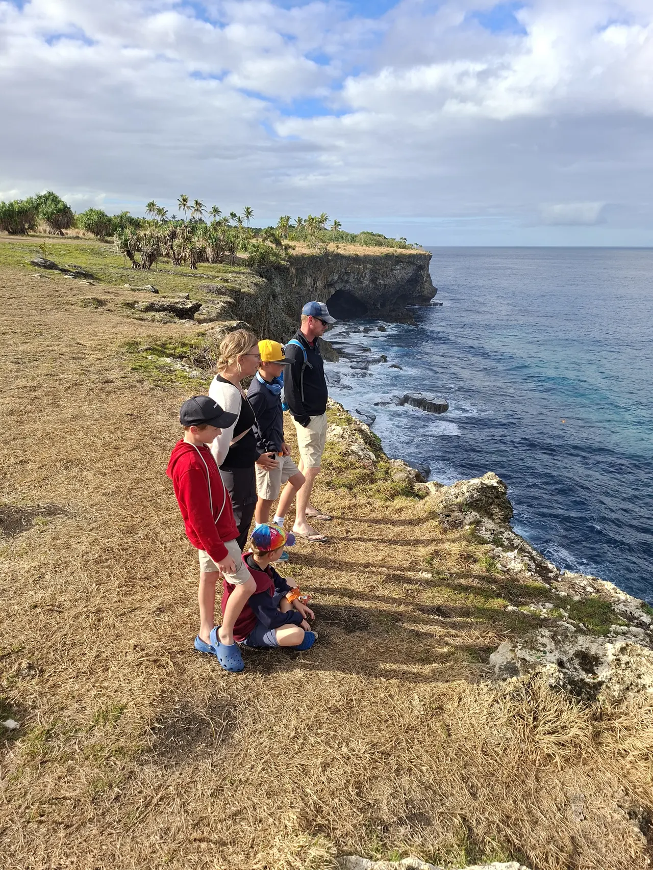 Tour guests looking out over a dramatic Tongatapu sea cliff